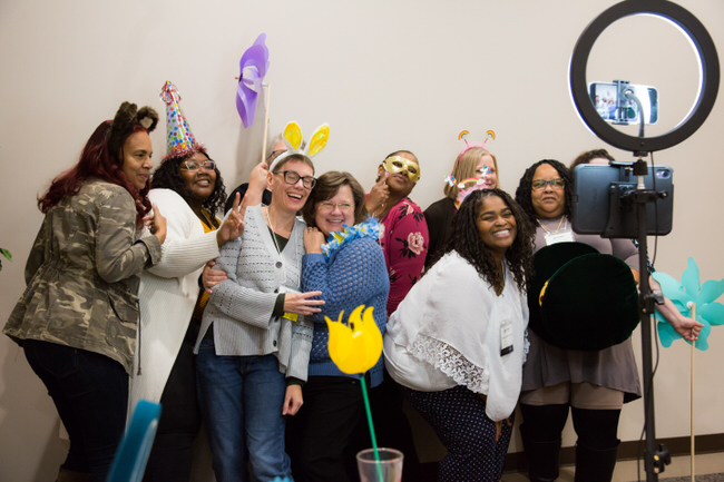 A large group of NCIMHA members enjoy donning masks and posing at the photo booth that was at the 2023 NCIMHA annual conference.