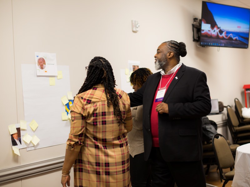 Members of NCIMHA stand in front of a dry erase board to collaborate on a project.