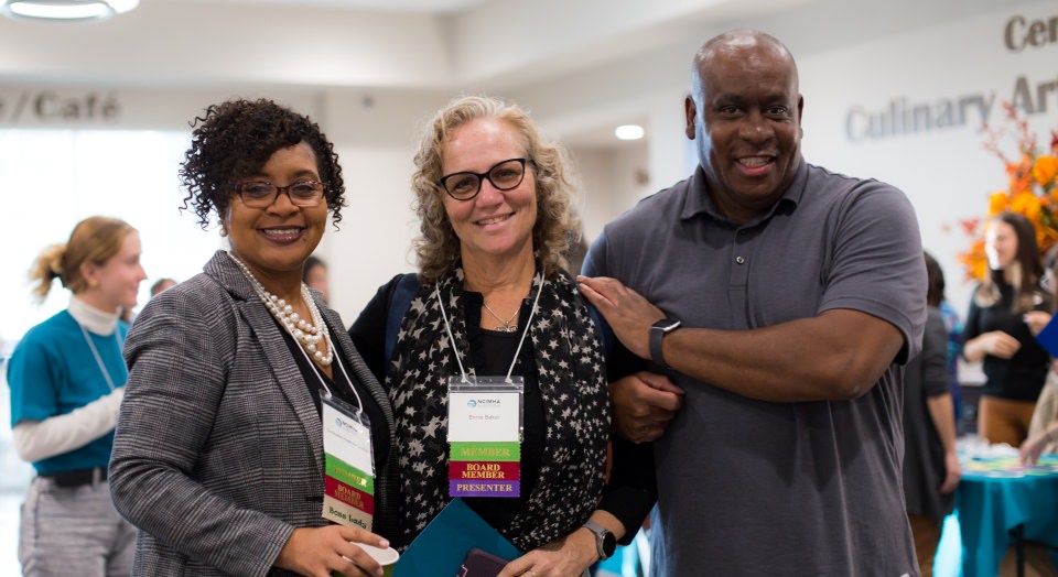 Three members of NCIMHA link arms in a show of support at the 2023 annual conference.